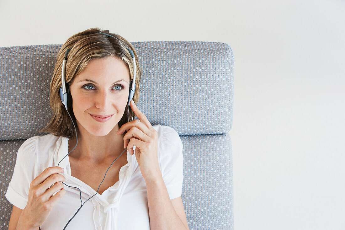 Woman listening to headphones in armchair, Palma de Mallorca, Balearic Islands, Spain