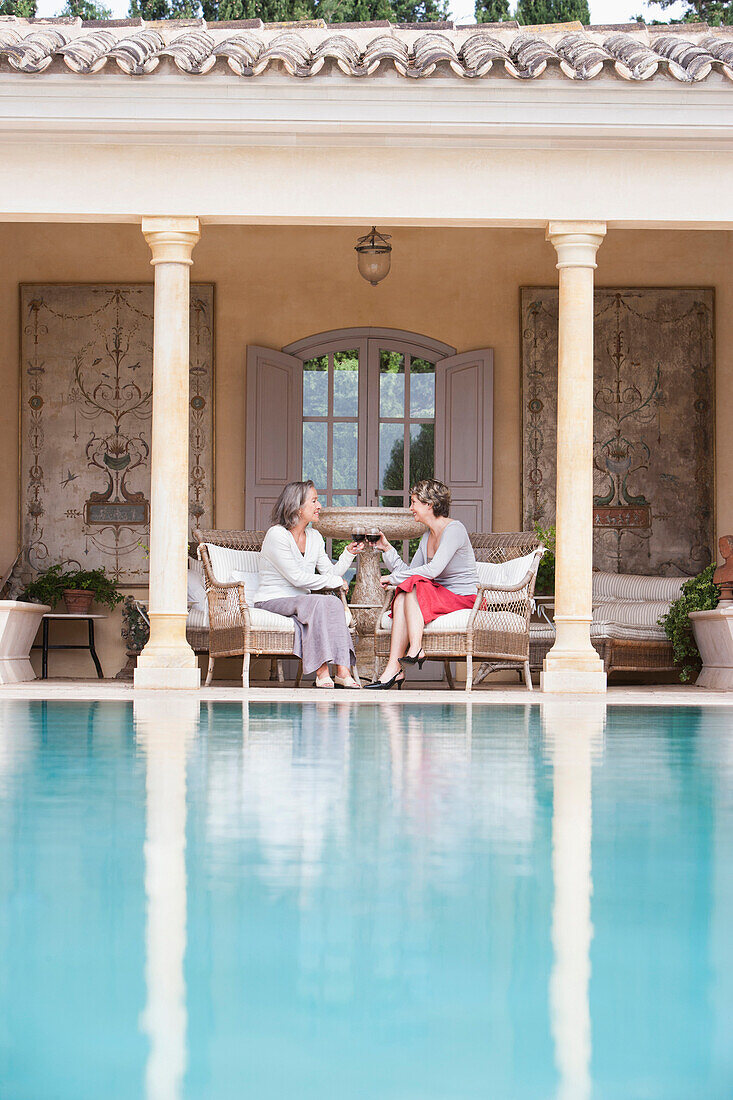 Women toasting each other by swimming pool, Palma de Mallorca, Balearic Islands, Spain