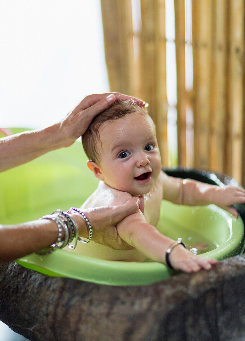 Kaukasische Mutter badet Baby in Plastikwanne, Ubud, Bali, Indonesien