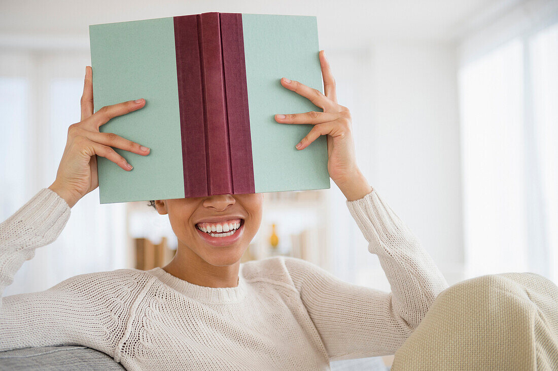 Black woman hiding behind book, Jersey City, New Jersey, USA