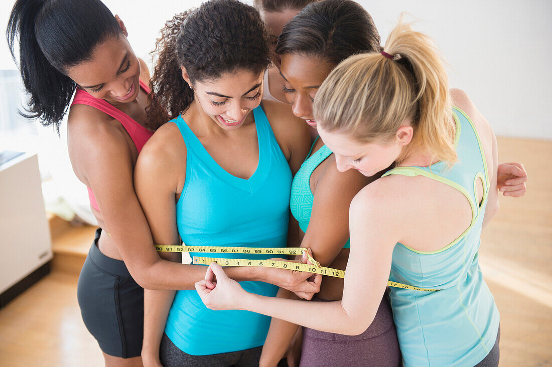 Women measuring their waistlines together, Jersey CIty, New Jersey, USA