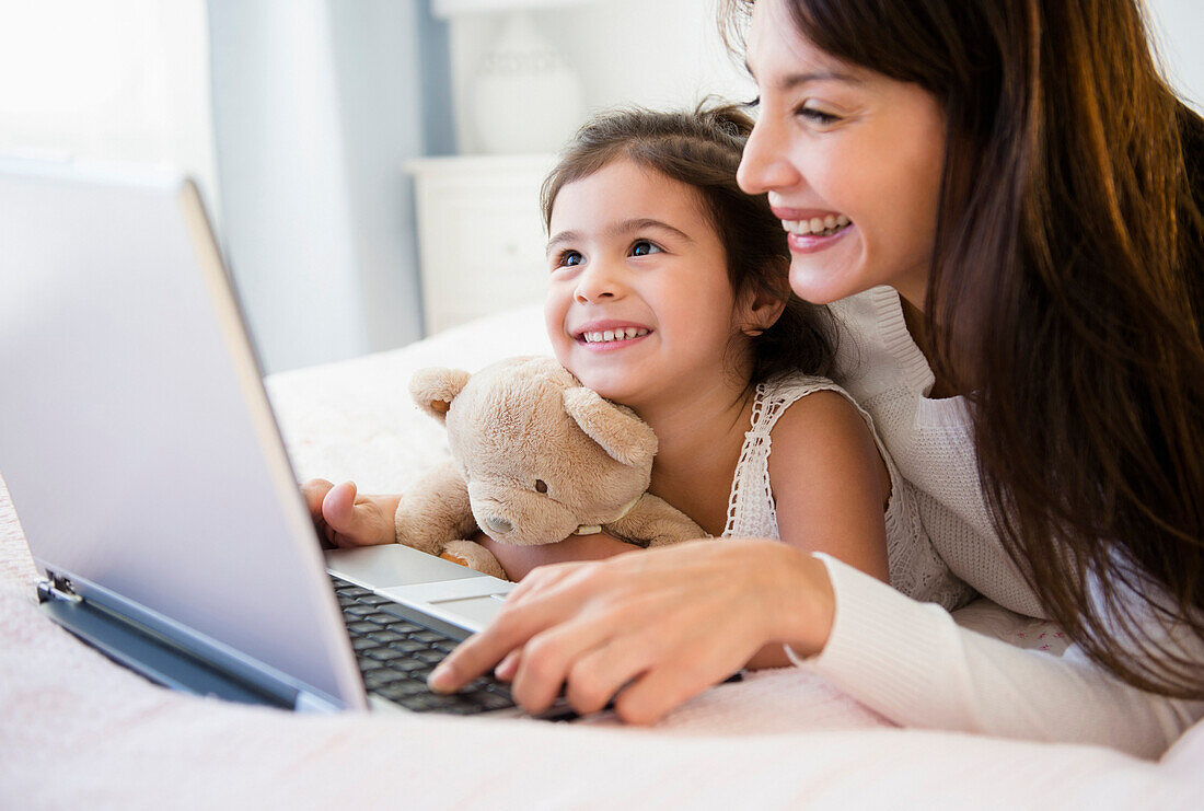 Hispanic mother and daughter using laptop together, Jersey City, New Jersey, USA