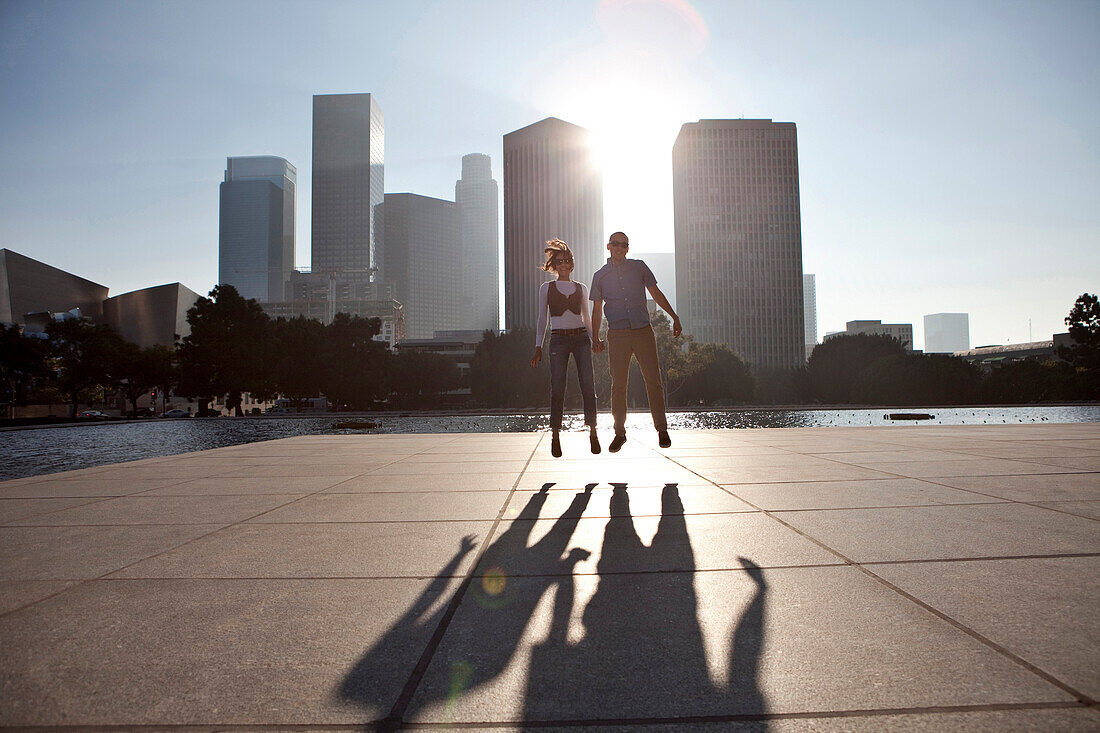 Couple casting shadows on urban waterfront, Los Angeles, CA, USA