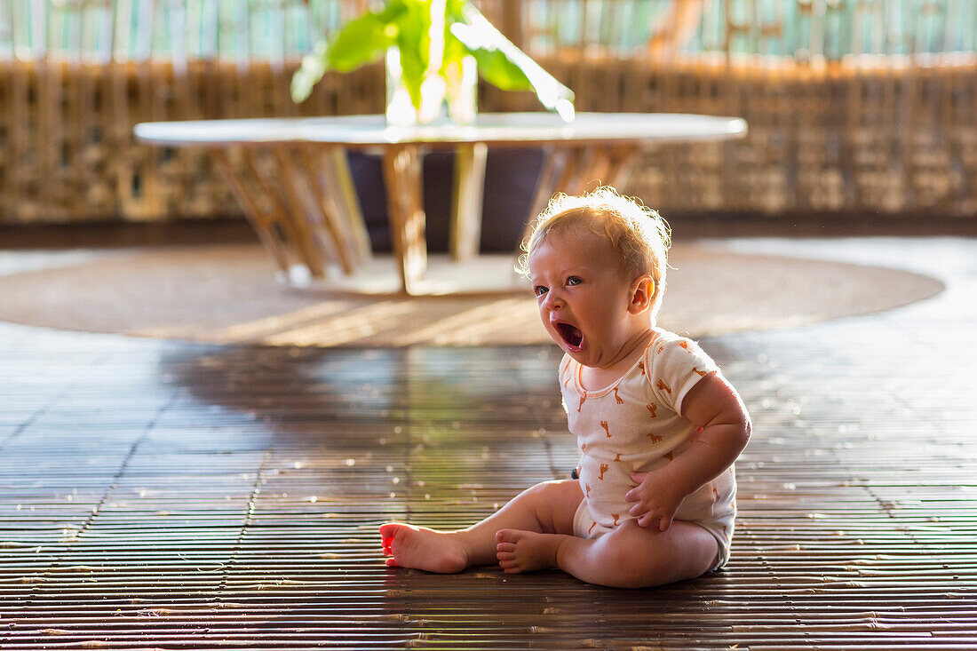 Caucasian baby yawning on floor, Ubud, Bali, Indonesia
