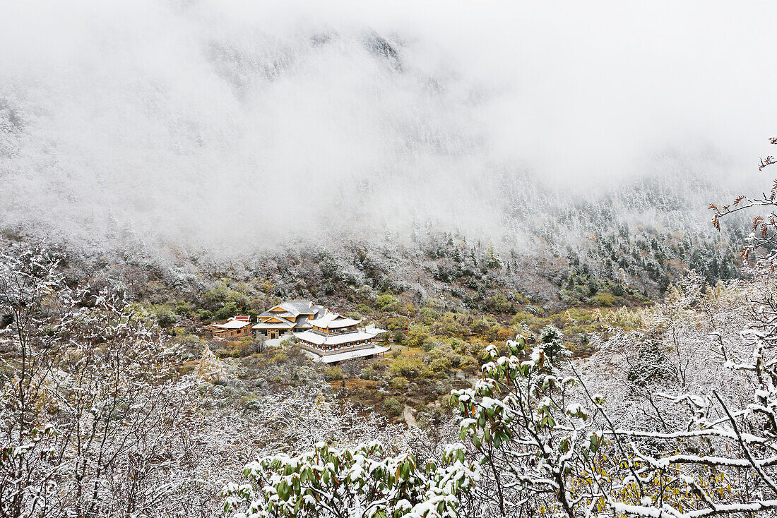'An Ancient Tibetan Buddhist Temple Between Two Snowy Mountain Slopes In The Mist; Huanglong, Sichuan Province, China'