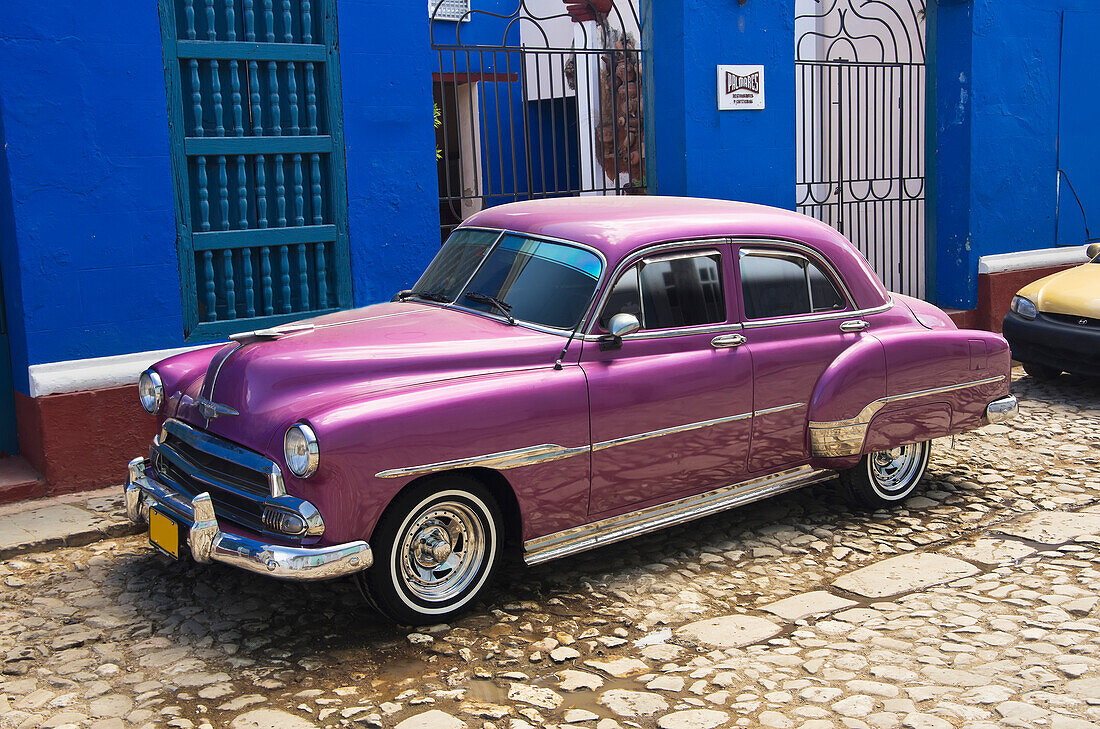 'Bright Purple Chevy Parked In Front Of A Blue Building; Trinadad, Sancti Spiritus, Cuba'