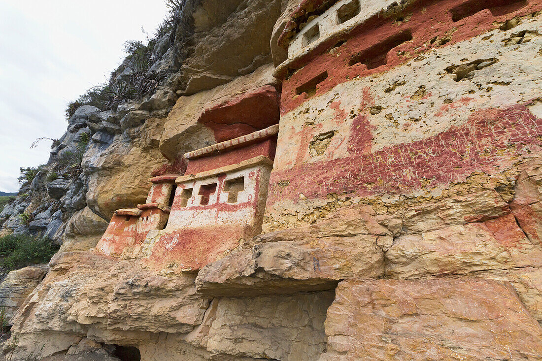 T-shaped windows in the chullpas (stone tomb chambers) of the Chachapoya culture with walls colored with red figures, nestled in the limestone cliffs of Cerro Carbón overlooking the Utcubamba River, Revash, Amazonas, Peru