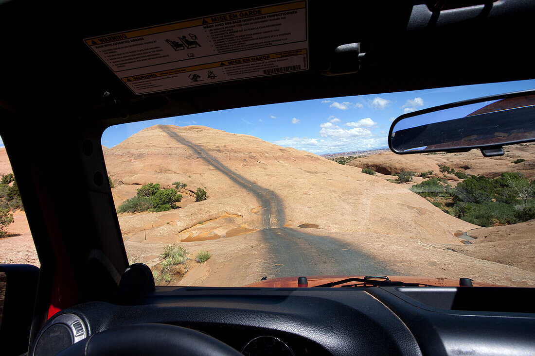 View of Remote Road Across Red Rocks Through Jeep Window, Moab, Utah, USA