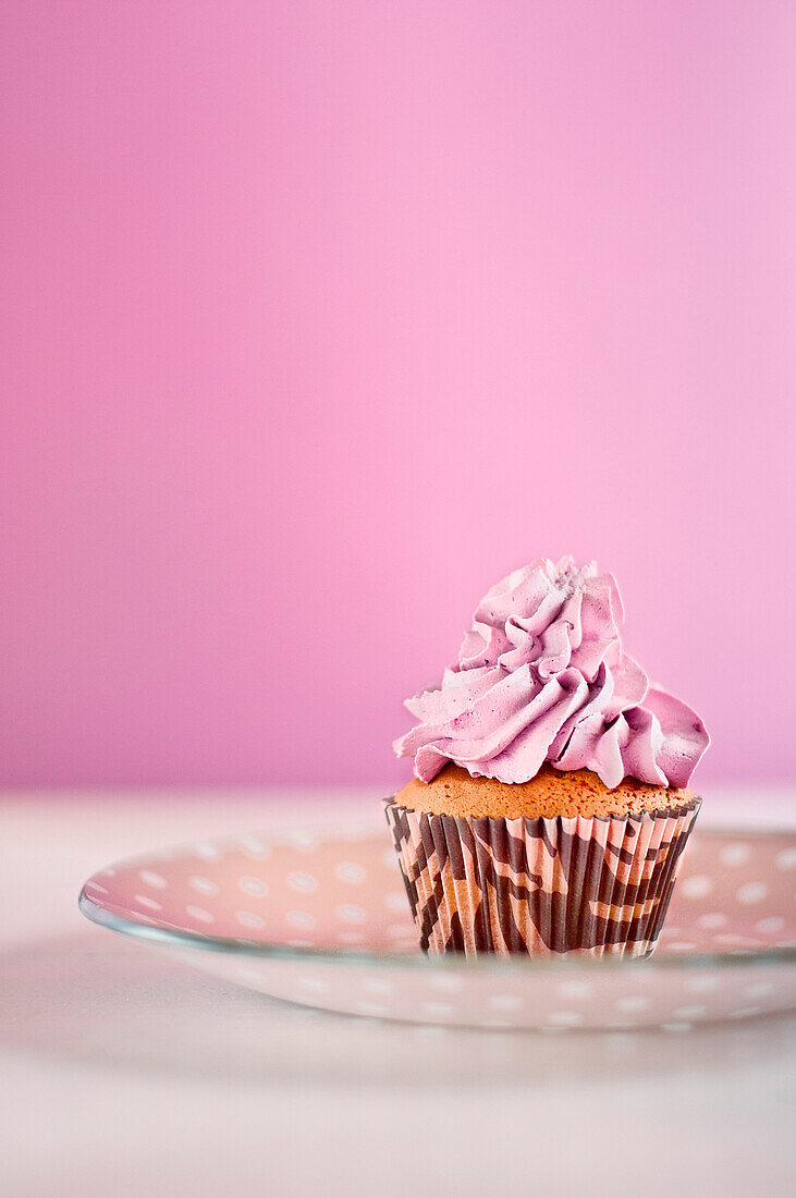 Cupcake with Icing on Dish Against Pink Background
