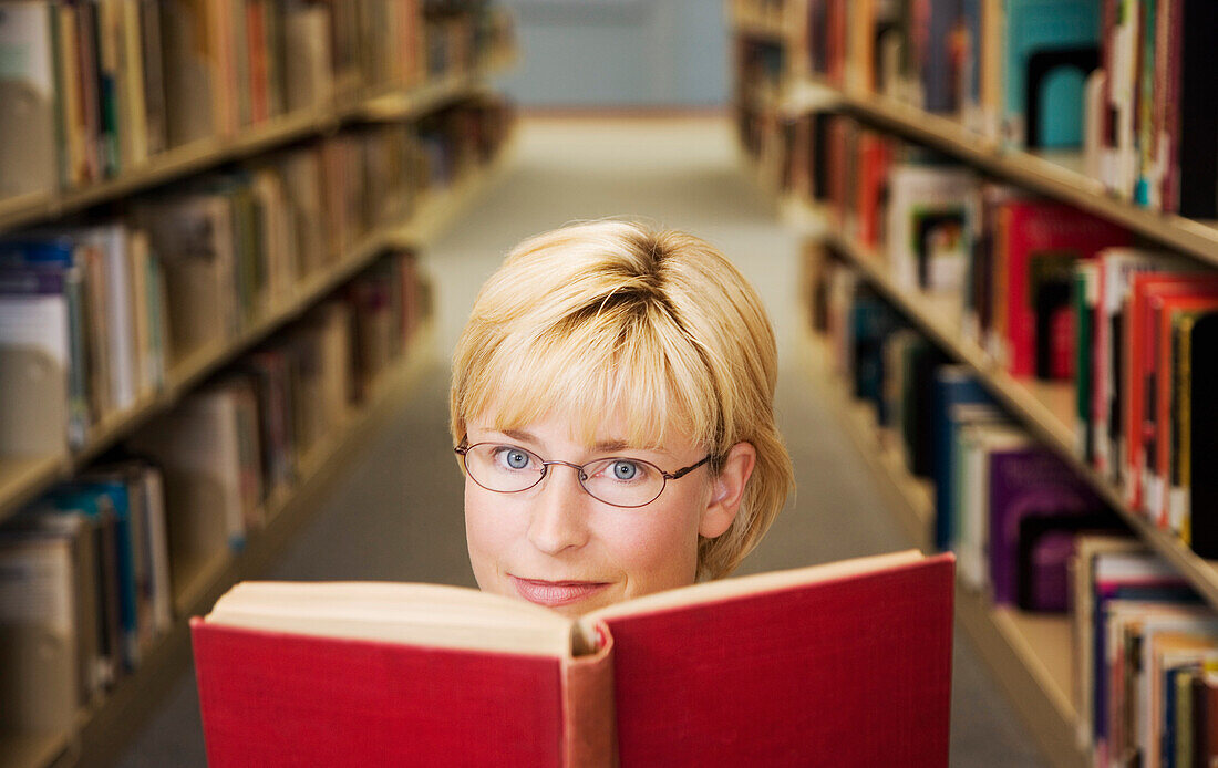 Woman Looking Up From A Book In The Library
