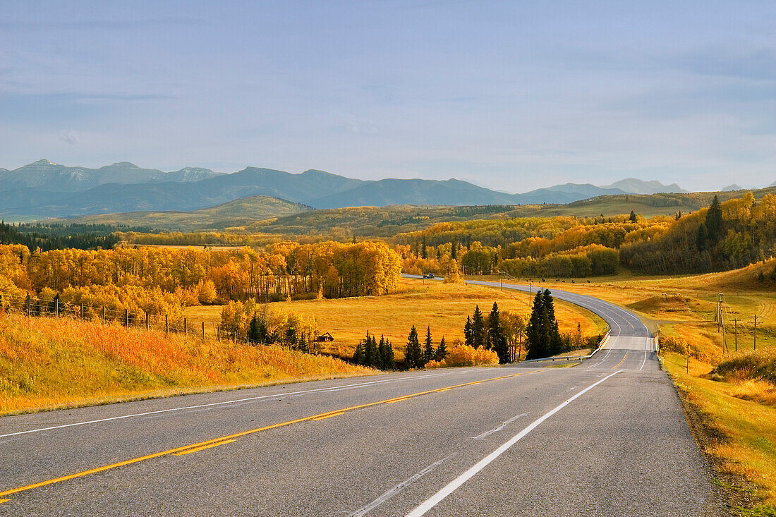 Highway And Distant Mountains With Trees In Alberta, Canada