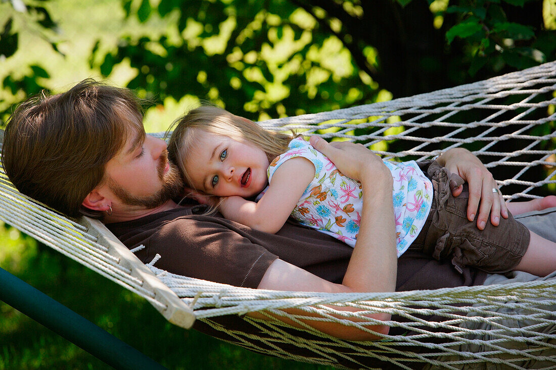 Father And Daughter Relaxing On Hammock