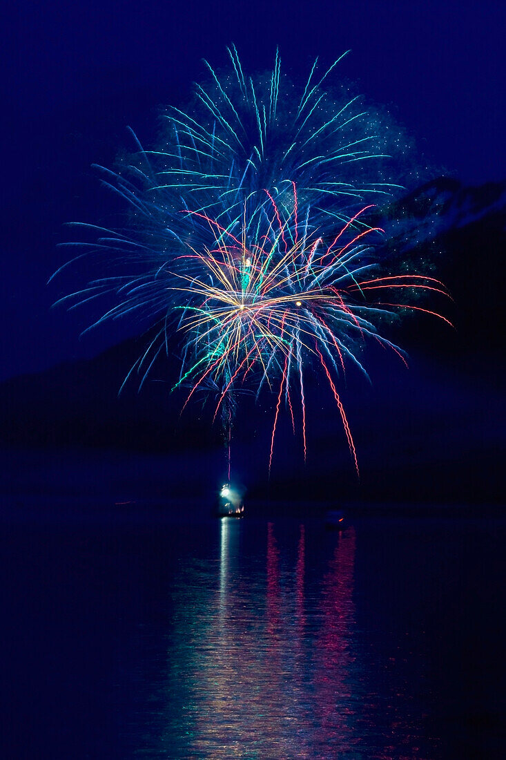 Fireworks Over The Water With A Mountain In The Background