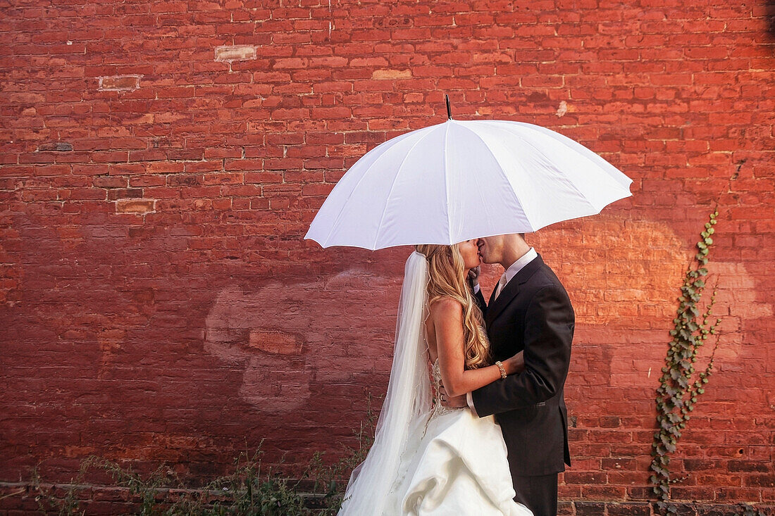 A Bride And Groom Under A White Umbrella