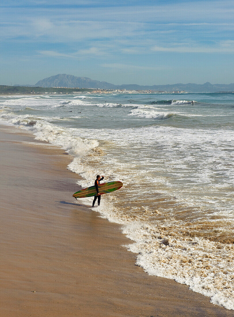 'Tarifa, Costa De La Luz, Cadiz, Andalucia, Spain; A Surfer On Hurricane Hotel Beach'