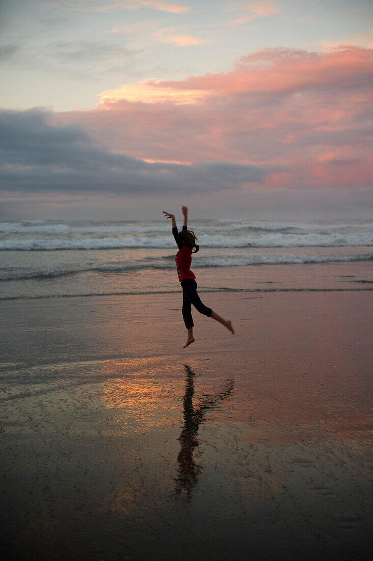 'A Girl Dances On The Beach At Sunset; Waihi Beach, New Zealand'