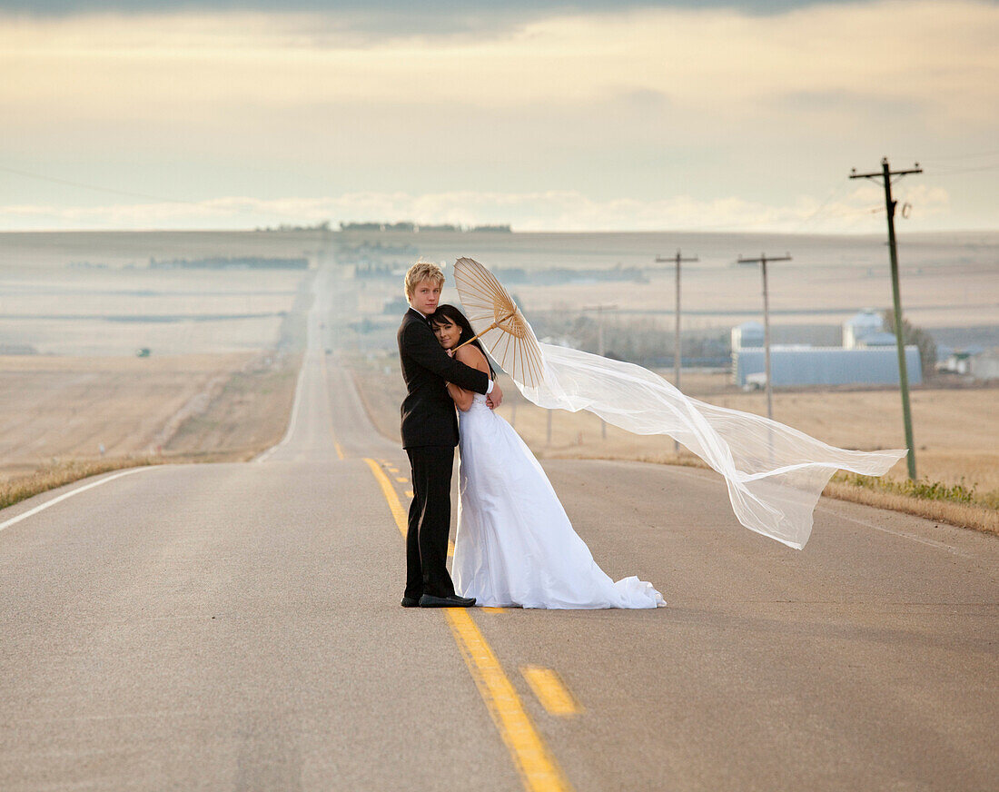 'Bride And Groom Posing On A Rural Road; Threehills, Alberta, Canada'