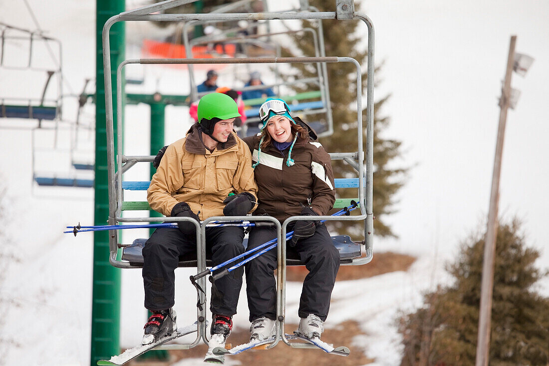 'A Man And Woman Riding A Chair Lift At A Ski Area; Red Deer, Alberta, Canada'