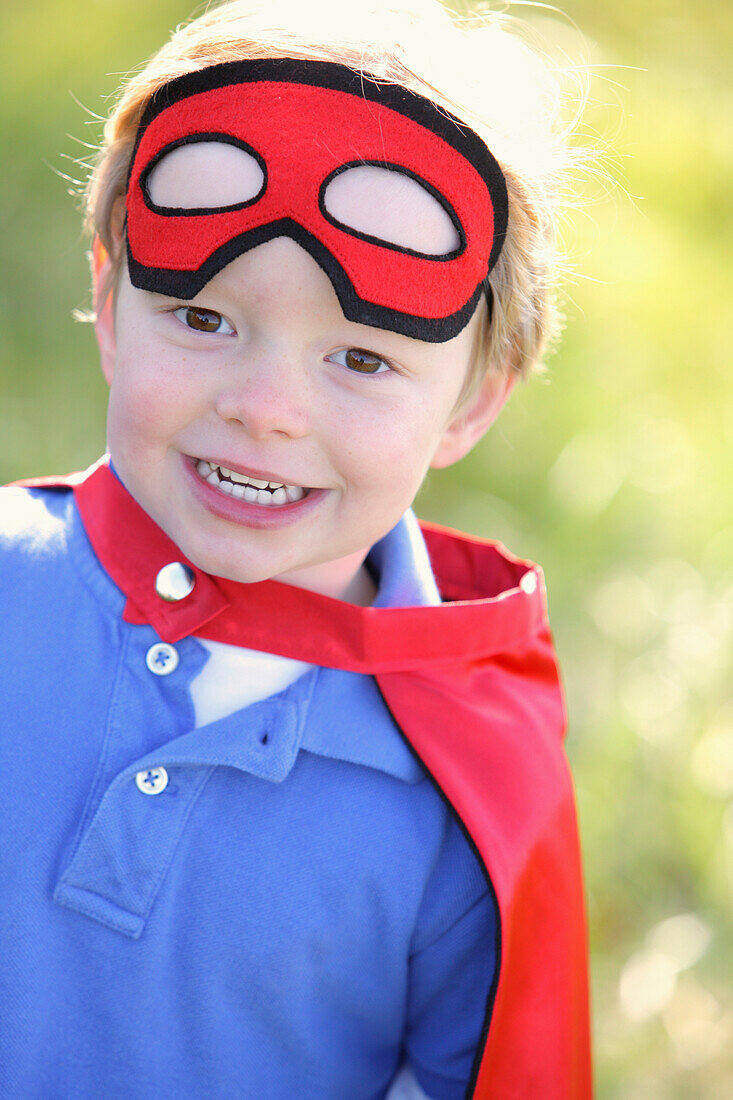 'Young Boy Playing Outdoors With A Cape And A Mask; Portland, Oregon, Usa'
