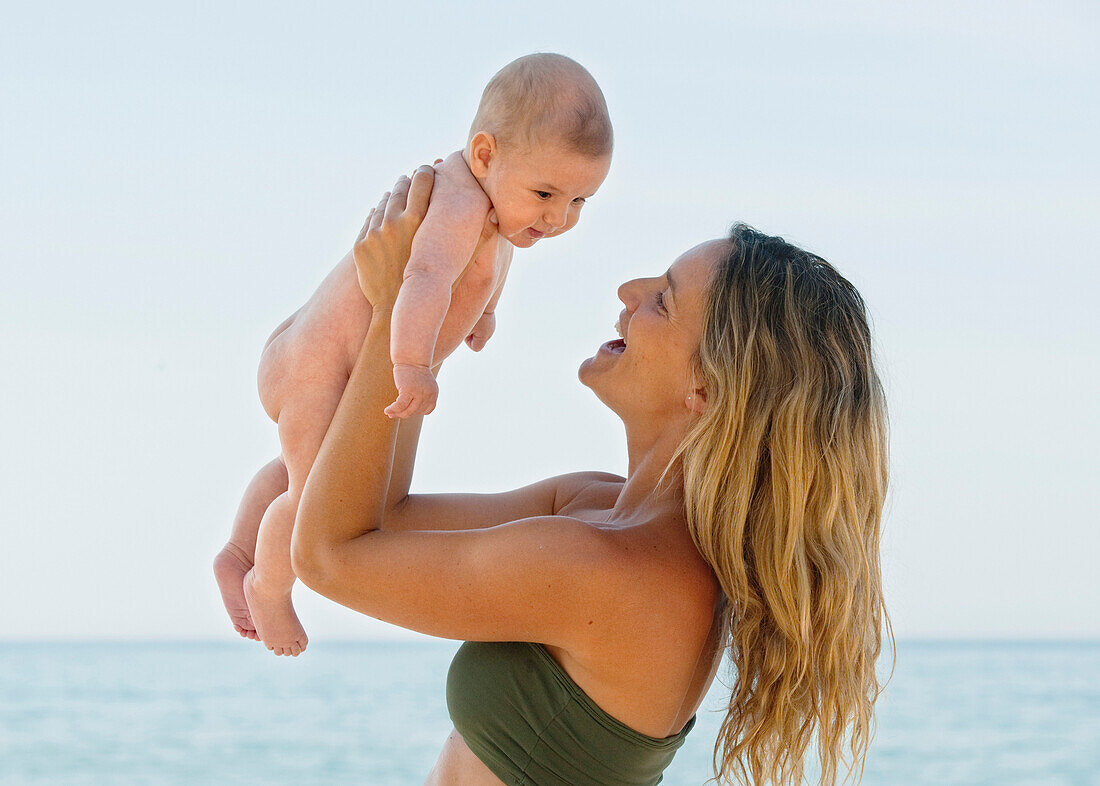 'A Mother Plays With Her Baby On The Beach; Banalmadena Costa, Malaga, Andalusia, Spain'