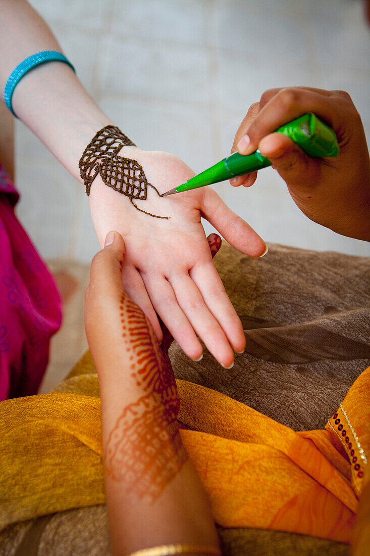 'A Woman Doing Henna Painting On Another Woman's Arm; Sathyamangalam, Tamil Nadu, India'