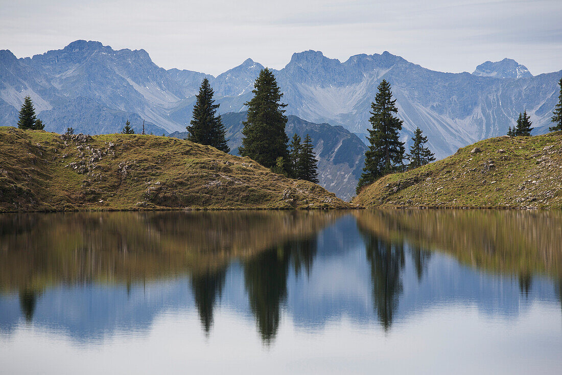 'Alpine Lake Reflecting A Mountain Range And Trees; Oberstdorf, Germany'