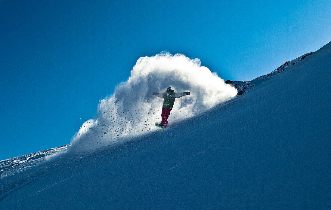 Austria, Montafon, snowboarder coming out of his powder turn like Jesus Chirst