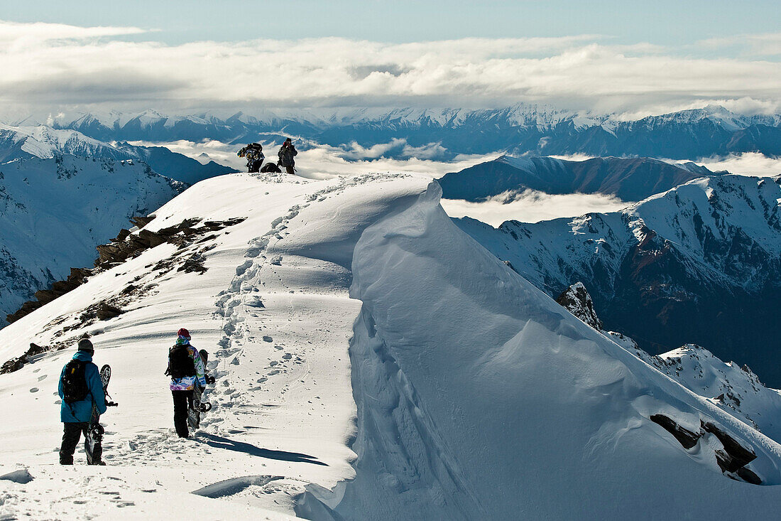 Snowboarder walking on a ridge  on top of a New Zealand Mountain, Wanaka
