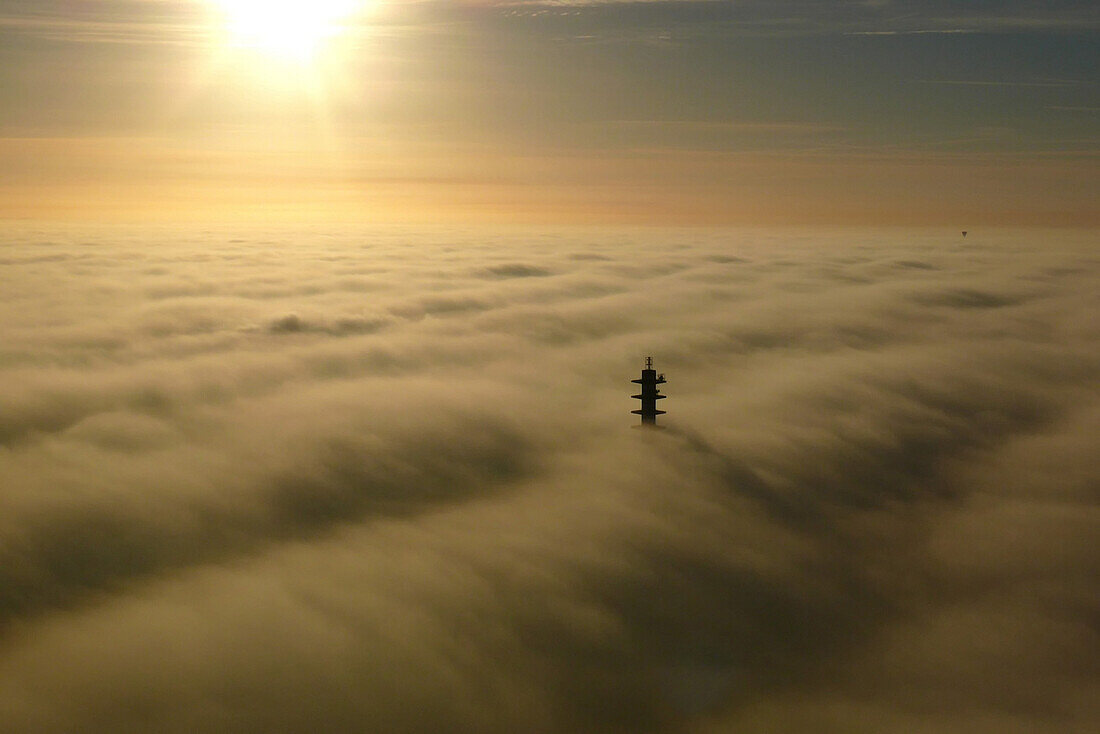 Relay antenna off emerging from the fog, facing the sun