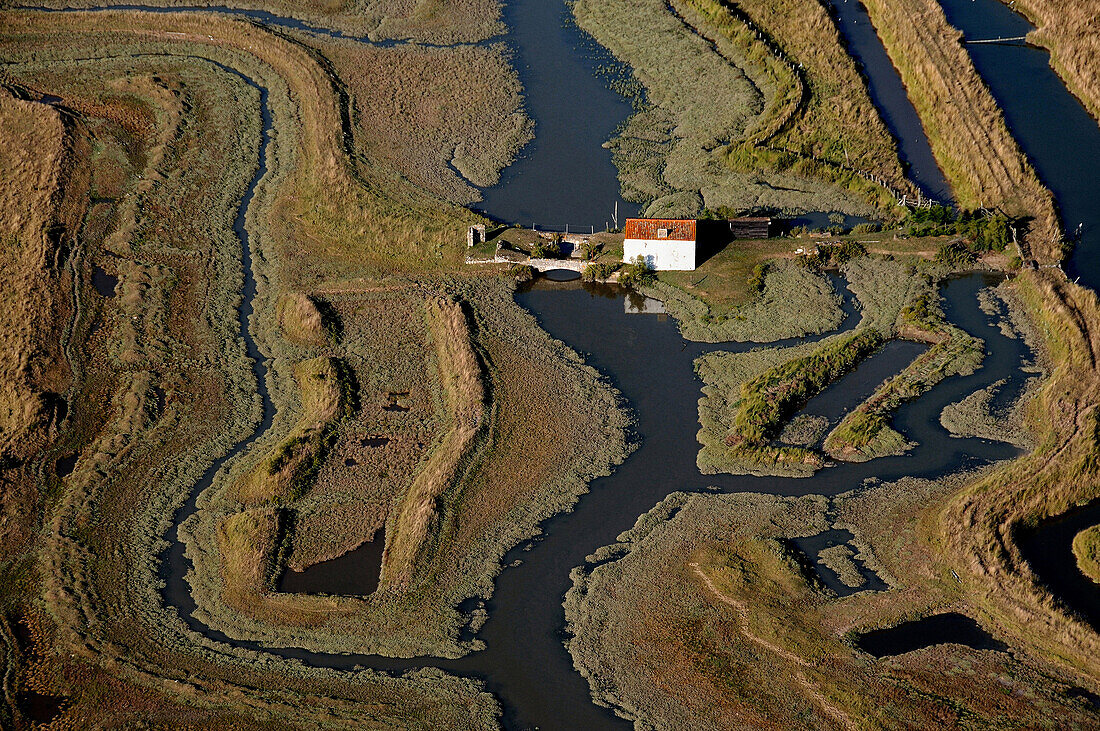 aerial view of the marsh crossed by a chanal. House on the top right. Bridge near the house