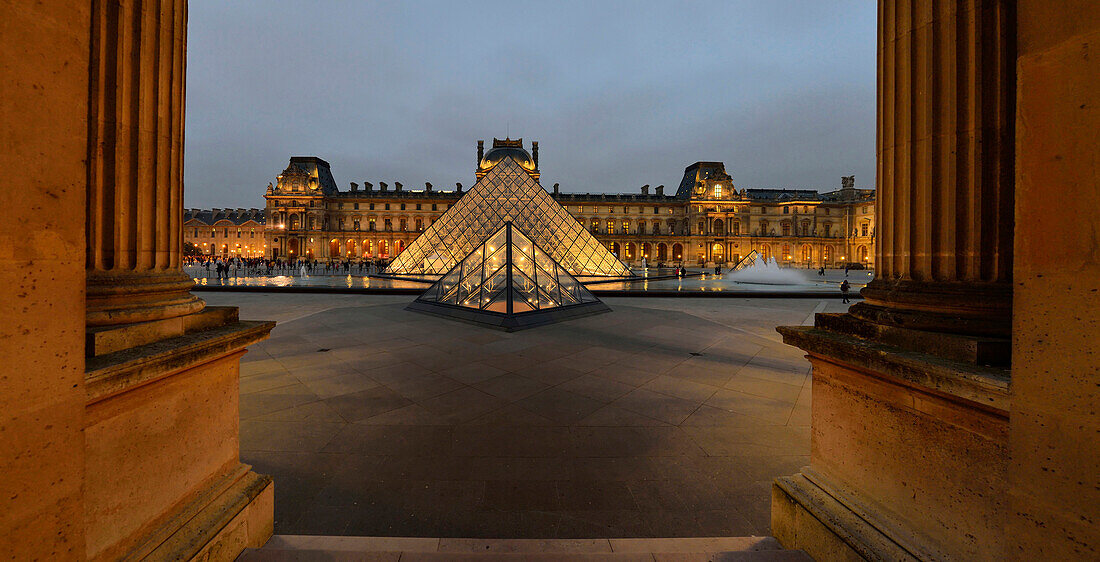 France. Overview of the Louvre in Paris at night. Two columns in the foreground