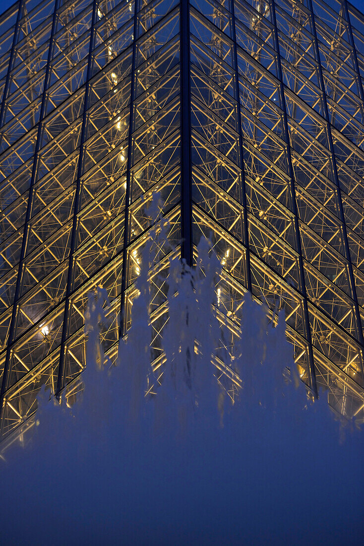 France. Water jet fountain in front of the Louvre Pyramid in Paris by night