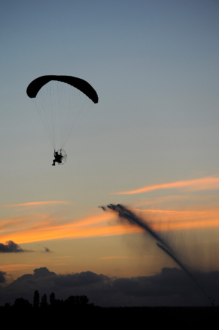 France, Montaigu, Vendée, paramotor flight at sunset. Water jet behind the veil