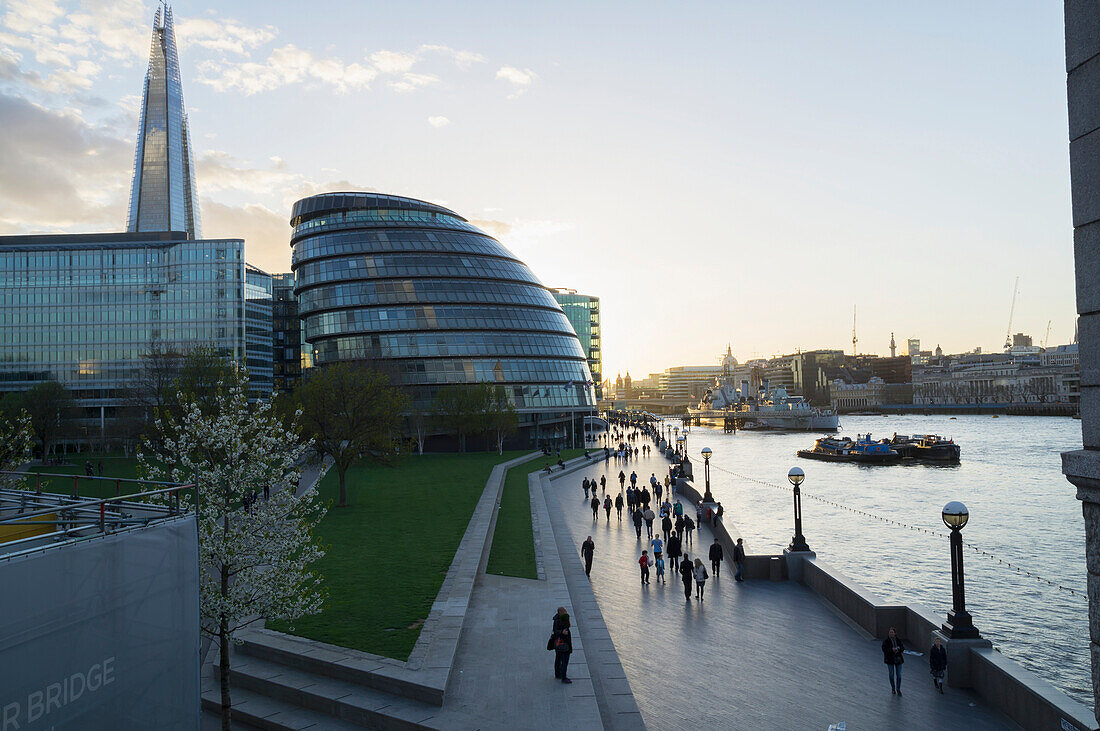 'Pedestrians and buildings along the promenade beside River Thames; London, England'