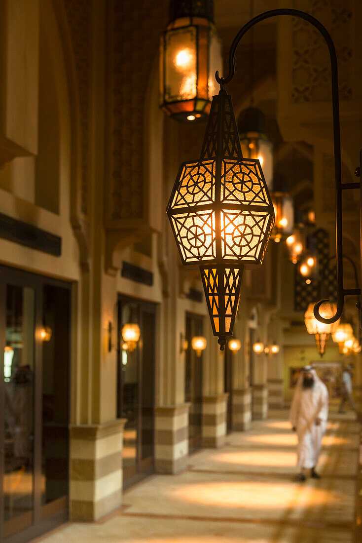 'Man in traditional arabic dishdasha outfit walking along corridor in shopping mall; Dubai, United Arab Emirates'