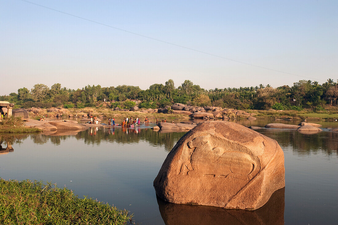 'A group of people bathing and cleaning clothes in the river; Hampi, Karnataka, India'