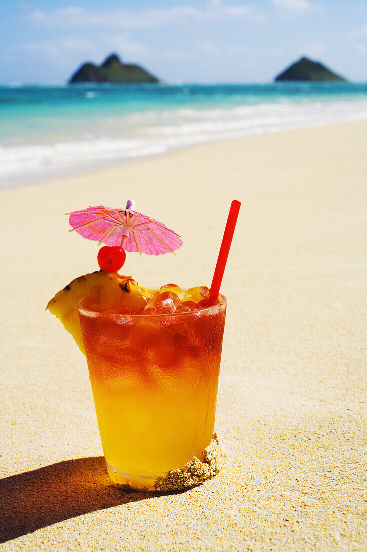 A Mai Tai Garnished With Pinapple And A Cherry, Sitting In The Sand On The Beach.