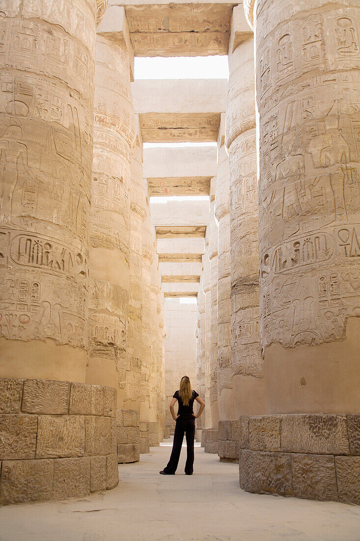 'A Woman Tourist Stands At The Base Of The Massive Columns In The Temples Of Karnak On The East Bank Of Luxor Along The Nile River; Egypt'