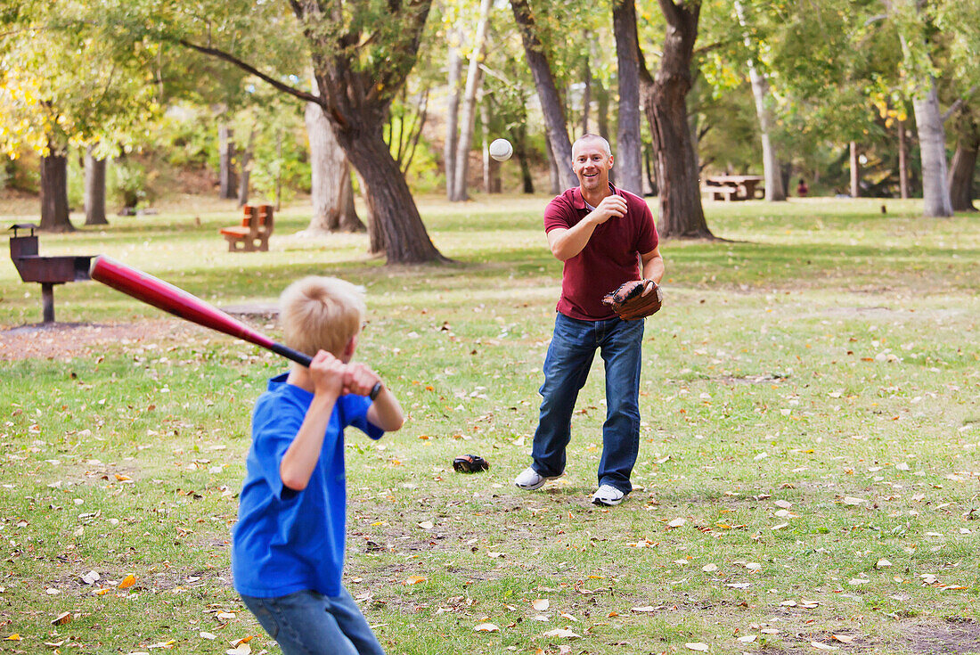'Father And Son Playing Baseball In A Park; Edmonton, Alberta, Canada'