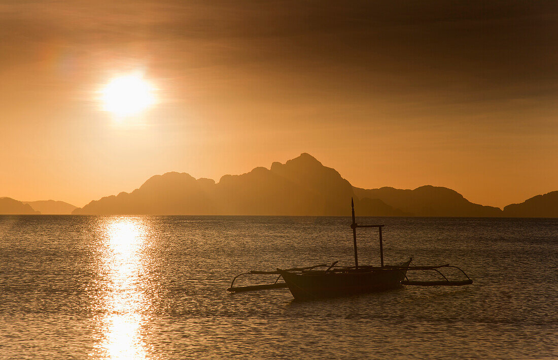 'A Boat Is Silhouetted In The Water At Sunset; Corong Corong, Bacuit Archipelago, Palawan, Philippines'