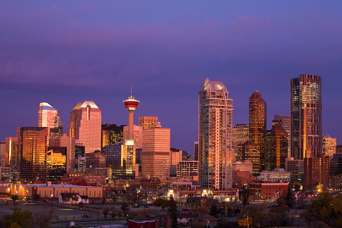 'Calgary Skyline At Dawn With City Lights And Deep Blue Sky With Buildings Reflecting The Orange Glow Of Sunrise; Calgary, Alberta, Canada'