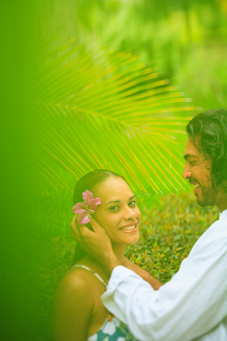 'A man puts a flower in a woman's hair at the bora bora nui resort and spa;Bora bora island society islands french polynesia south pacific'