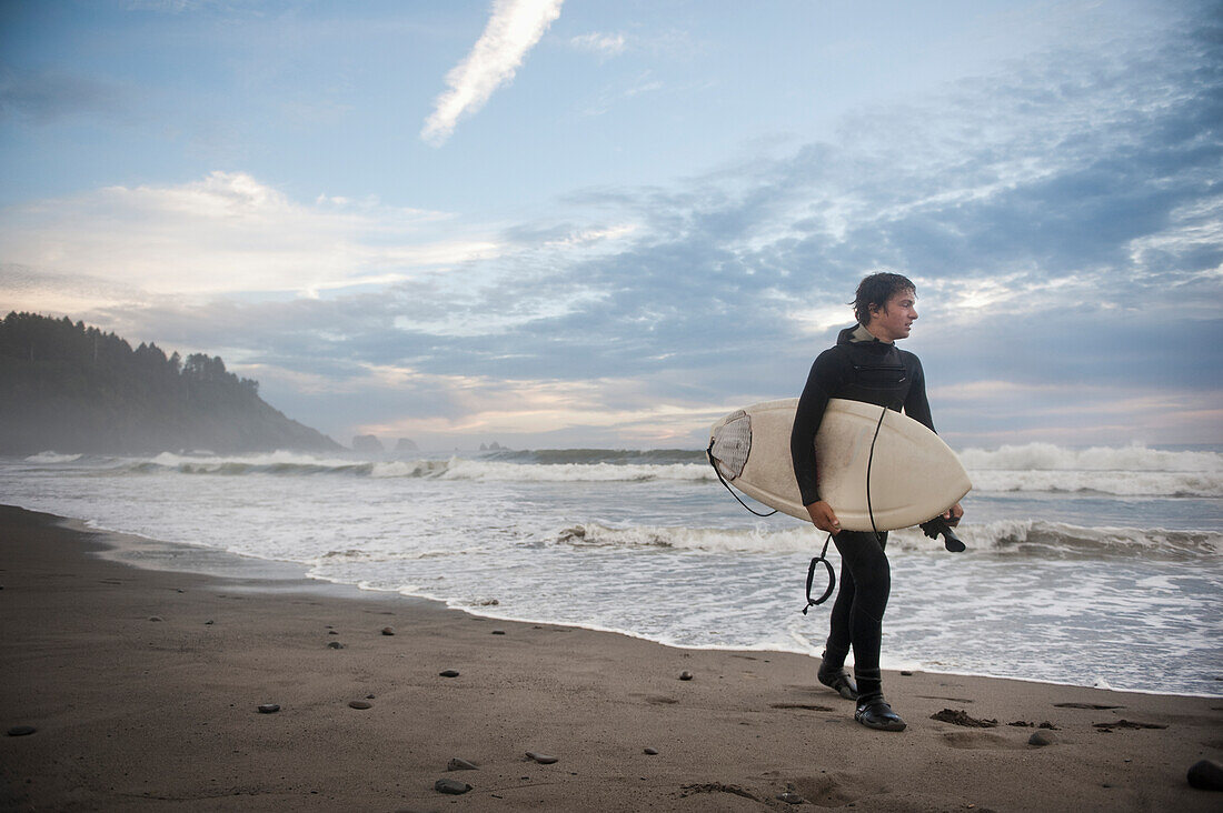 'A Young Man Carries His Surfboard Down The Beach; La Push Washington United States Of America'