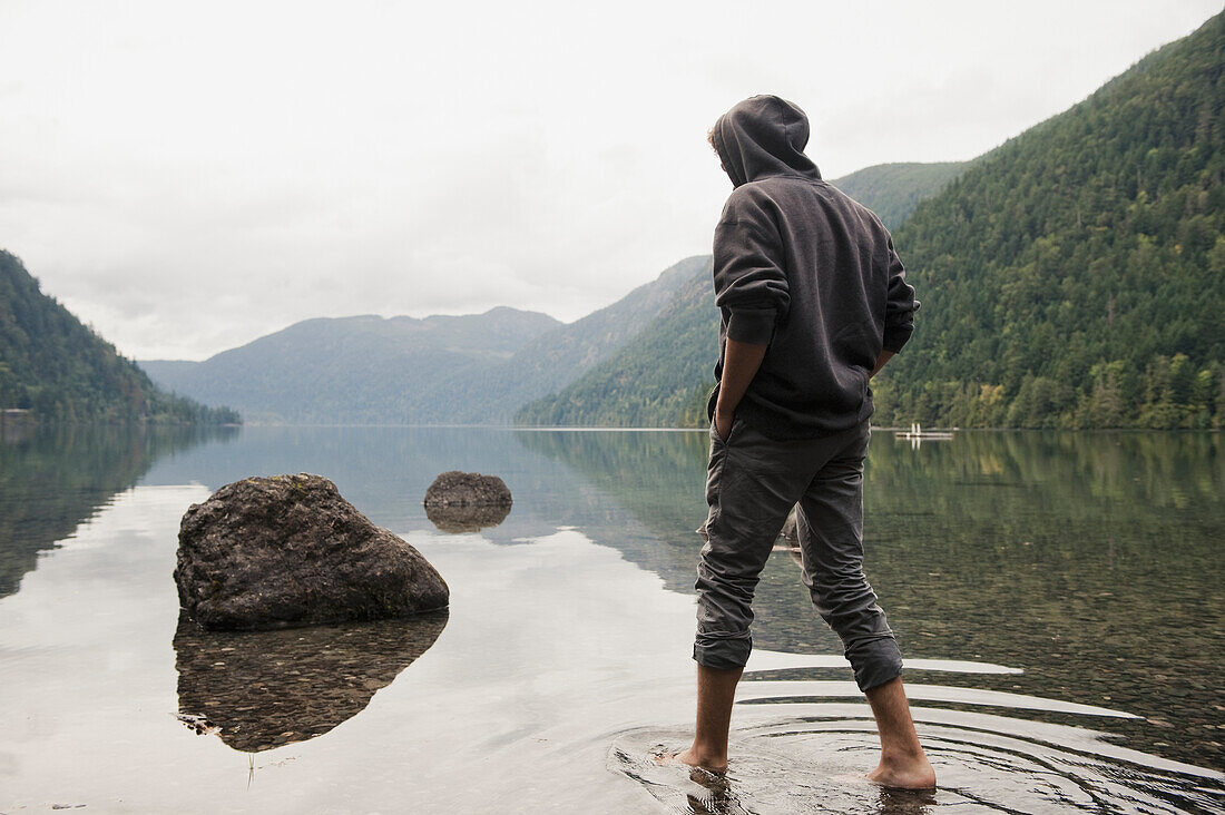 'A Young Man Wades In Shallow Water On Cameron Lake; British Columbia Canada'