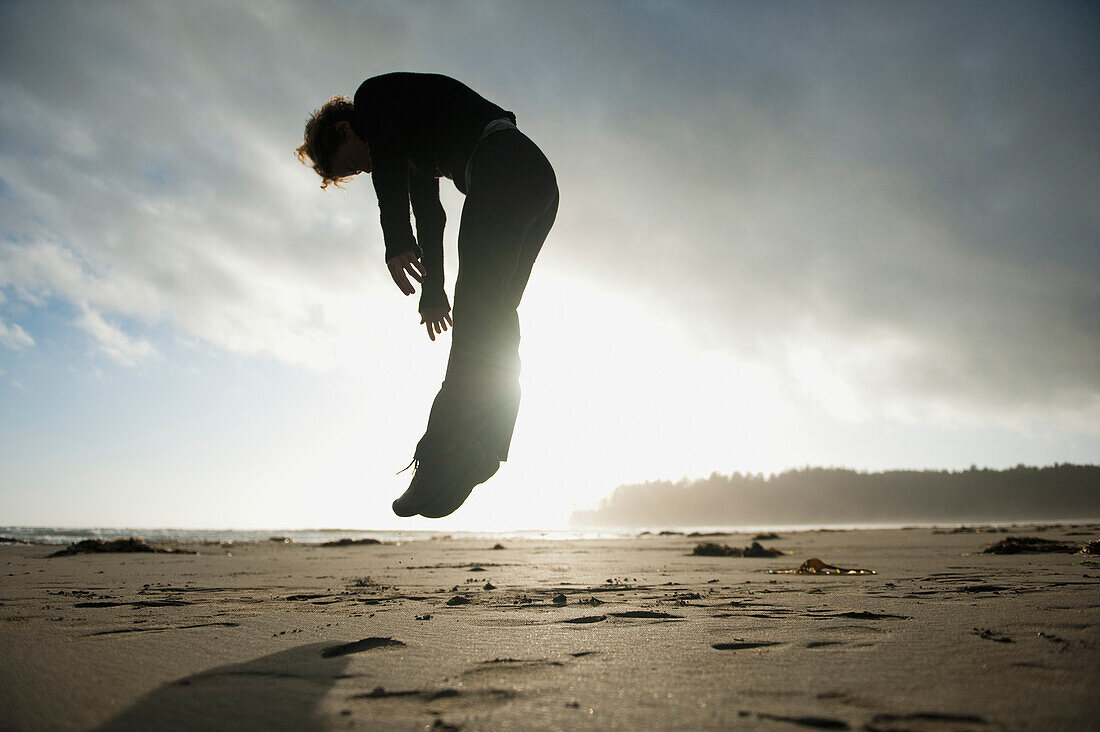 'A Person Jumps In The Air On Hobuck Beach At Sunset; Washington United States Of America'