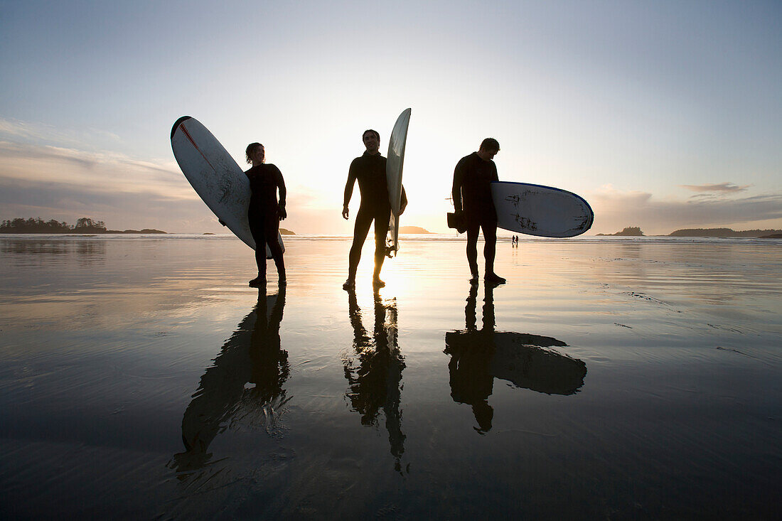 'Silhouette Of Three Surfers Carrying Surfboards; Chesterman Beach Tofino Vancouver Island British Columbia Canada'