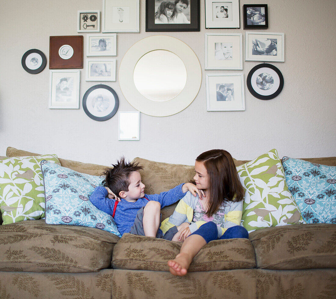 'Brother and sister sitting on a couch at home; Victoria, British Columbia, Canada'