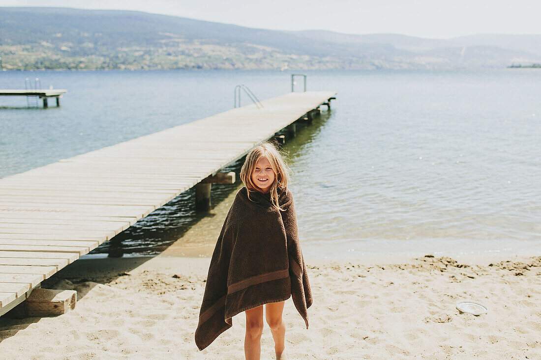 'A girl stands on the beach at the edge of Lake Okanagan; Peachland, British Columbia, Canada'