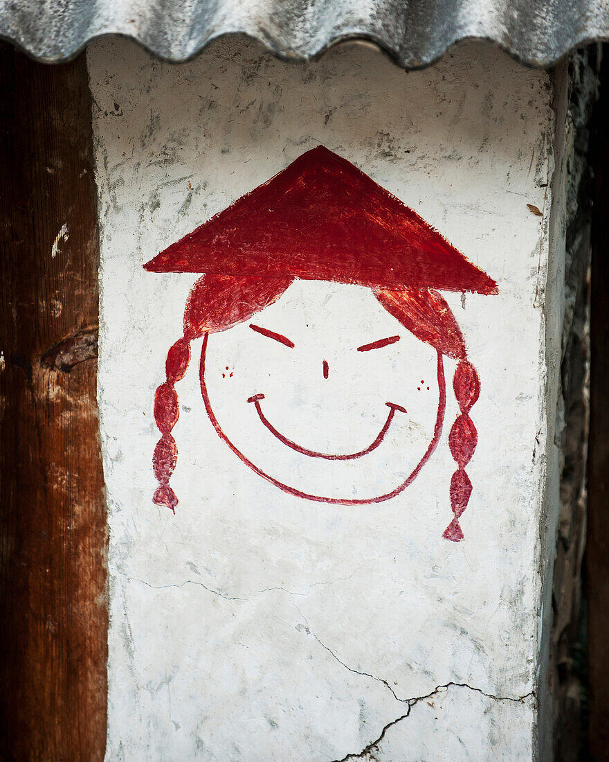 'Drawing of a face with a conical hat on a bathroom wall; Tiger Leaping Gorge, Yunnan, China'