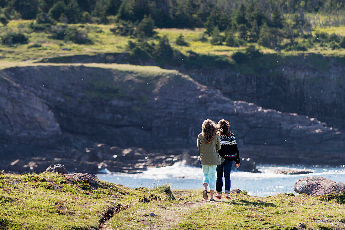 'A mother and daughter stand on a trail overlooking the Atlantic coastline at Cape Spear; St. John's, Newfoundland and Labrador, Canada'